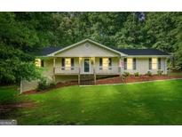 Charming single-Gathering home featuring a covered front porch and a well-maintained lawn with mature trees at 185 Downybrook Ln, Fayetteville, GA 30215