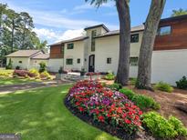 Stunning two-story home featuring a well-manicured lawn and beautiful flowerbeds, set against a bright blue sky at 2775 Club Valley Ct, Jonesboro, GA 30236