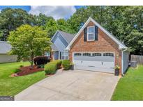 Charming home featuring a well-manicured lawn, brick accents, and an attached two-car garage at 3511 Cherry Blossom Ct, Loganville, GA 30052