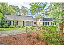 Charming single-story home featuring black shutters, a dark roof, and a traditional facade surrounded by mature trees at 522 Golfview, Peachtree City, GA 30269