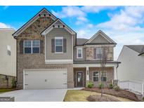Two-story home with brick and stone accents, two-car garage, and manicured front yard at 714 Bristol Dr # 279A, Loganville, GA 30052