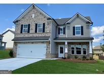 Beautiful two-story home featuring stone and gray shingle accents, a two-car garage, and manicured landscaping at 714 Bristol Dr # 279A, Loganville, GA 30052