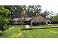 Charming brick home featuring lush green lawn, mature trees, and meticulous landscaping, radiating curb appeal at 4710 Cedar Brook Se Dr, Conyers, GA 30094