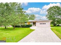 Charming single-story home with a well-manicured lawn, a long driveway, and an attached three-car garage at 741 Greenhill Ne Dr, Conyers, GA 30012
