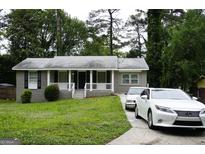 Charming grey brick home featuring a well-manicured lawn, front porch and a private driveway at 39 Mcferrin Cir, Riverdale, GA 30274