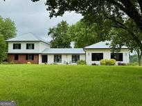 Charming home with lush green lawn, beautiful landscaping, and a metal roof at 360 Morgan Mill Rd, Brooks, GA 30205