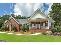 Charming brick home with a well-manicured lawn, covered porch, and lush landscaping at 245 Edenwylde Ct, Hampton, GA 30228