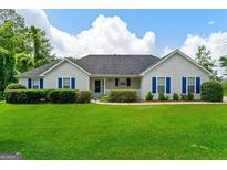 Charming single-story home with blue shutters, manicured lawn, and lush green landscaping at 227 Ferguson Ave, Locust Grove, GA 30248
