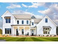Stunning two-story white farmhouse with covered front porch and well-manicured lawn at 25 Oak Rd, Locust Grove, GA 30248