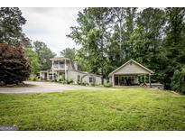 Charming two-story home featuring a lush green lawn, multiple buildings, and mature trees at 300 Peggy Cole Bridge Rd, Villa Rica, GA 30180