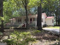 Charming single-story home with a red roof, inviting porch, and well-maintained yard nestled among mature trees at 2306 Old Lower River Rd, Douglasville, GA 30135