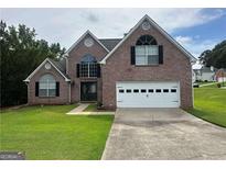 Charming two-story brick home featuring a two-car garage, well-manicured lawn, and classic curb appeal at 12189 Lauren Way, Fayetteville, GA 30215