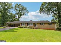 Charming ranch-style home featuring a well-manicured lawn and an inviting facade with large trees at 3212 Georgian Woods Cir, Decatur, GA 30034