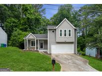 Charming home featuring light gray siding, an attached garage, and a welcoming front yard with a well-manicured lawn at 2069 Countydown Ln, Stone Mountain, GA 30088