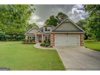 Charming brick home with an attached two car garage, manicured lawn, and mature trees at 9187 Golfside Cir, Covington, GA 30014