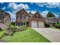 Beautiful two-story brick home with a two-car garage, a manicured lawn, and a stone garden bed at 705 Lawton Bridge Sw Rd, Smyrna, GA 30082
