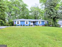 Charming blue ranch style home with a lush green lawn, mature trees, and a welcoming front entrance at 4579 S Amberly S Ct, Atlanta, GA 30360