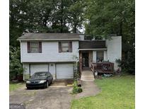 Split-level home with a two-car garage, wooden deck, stone porch and mature trees at 6884 Red Maple Ct, Rex, GA 30273