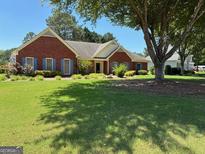 Charming brick home with a large, well-manicured front lawn and mature shade trees at 9361 Arbor Glenn Ct, Jonesboro, GA 30236