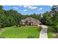 Beautiful, stone-clad home with lush lawn and driveway on a sunny day at 185 Platinum Ridge Pt, Fayetteville, GA 30215