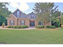 Charming brick home featuring well-manicured lawn, lush shrubbery, and mature trees in a peaceful setting at 260 Bonnie Ln, Fayetteville, GA 30215