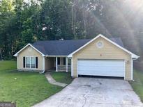 Inviting single Gathering home featuring an attached two-car garage and charming front yard at 8519 Glenwoods Dr, Riverdale, GA 30274