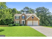 Charming two-story brick home featuring a well-manicured lawn and a two-car garage at 7505 Brookwood Way, Cumming, GA 30041