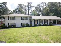 Charming white brick home features a well-manicured lawn and a covered carport at 3686 Calmer Cir, East Point, GA 30344