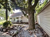 Charming home with a large tree, stone pathway, and inviting front porch with furniture at 6192 Collins Ne St, Covington, GA 30014
