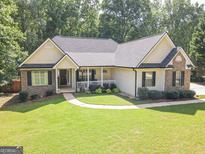 Charming single-story home featuring a well-manicured lawn, brick accents, and a welcoming front porch at 65 Cold Harbor Ct, Sharpsburg, GA 30277