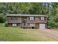 Charming split-level home with wood siding, a front porch, a garage and a lush front yard at 5804 Macedin Dr, Douglasville, GA 30135
