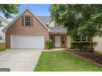 Charming two-story brick home featuring an attached two-car garage and a well-maintained front lawn and manicured landscaping at 308 Sarasota Ln, Locust Grove, GA 30248