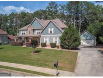 Charming two-story home with a stone and teal exterior, lush lawn, mature trees, and an attached two-car garage at 125 Seawright Dr, Fayetteville, GA 30215
