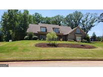 Charming home featuring a lush green lawn with mature trees and beautifully landscaped yard at 90 Alcovy Reserve Way, Covington, GA 30014