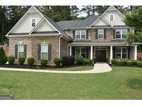 Beautiful two-story home featuring brick and stone accents, a manicured lawn, and a welcoming front porch at 6660 Canyon Cv, Cumming, GA 30028