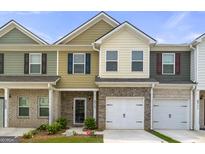 Charming townhome featuring a brick facade, a one-car garage, and colorful exterior paint at 8717 Lakeview Commons, Jonesboro, GA 30238