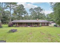 Charming single-story home featuring a welcoming porch, mature trees, and a spacious front yard at 5618 Shadow Rock Dr, Lithonia, GA 30058