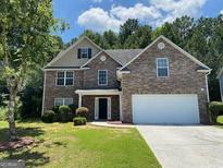 Charming two-story brick home features a well-manicured lawn and attached two-car garage at 1472 Queenie Smith Ne Rd, Conyers, GA 30012