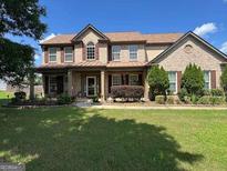 Charming two-story home with a well-maintained lawn and inviting front porch, with beautiful brick facade at 7880 Cavendish Pl, Suwanee, GA 30024