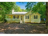 Charming yellow home with a welcoming front porch and mature trees providing shade at 419 Jeffery Dr, Locust Grove, GA 30248