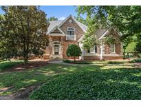 Charming stone home featuring a lush front yard with mature trees and manicured landscaping at 914 Champions Way, Mcdonough, GA 30252