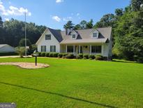 Charming home with a large manicured lawn, mature trees, and a welcoming front porch at 424 Ivey Edwards Ln, Mcdonough, GA 30253