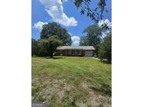 Charming brick home featuring an attached garage, inviting front porch and a well-maintained, expansive front yard at 5061 Old Atlanta Rd, Hampton, GA 30228