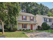 Charming two-story home with a well-maintained lawn, red shutters and door, and mature trees at 162 Watercress Ct, Stockbridge, GA 30281