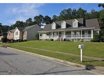 Charming two-story home with a welcoming porch and well-manicured lawn, nestled in a suburban neighborhood at 4680 Duval Point Sw Way, Snellville, GA 30039