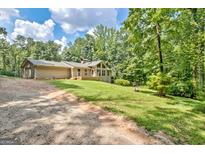 Charming one-story home with a deck and a lush, green lawn surrounded by mature trees at 351 Weldon Rd, Palmetto, GA 30268