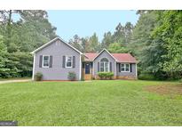 Charming one-story home featuring gray siding, black shutters, and a well-maintained front yard at 85 Holly Springs Rd, Sharpsburg, GA 30277