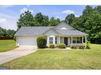 Charming single-story home featuring a manicured lawn, attached garage, and inviting front porch at 120 Bramble Bush Trl, Covington, GA 30014
