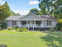 Charming single-story home with a well-manicured lawn, gray siding, and welcoming front porch at 1120 Rawlings Dr, Rutledge, GA 30663