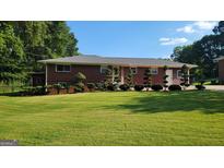 Charming brick home featuring a well-manicured front yard and beautiful landscaping at 1527 Patricia Dr, Morrow, GA 30260
